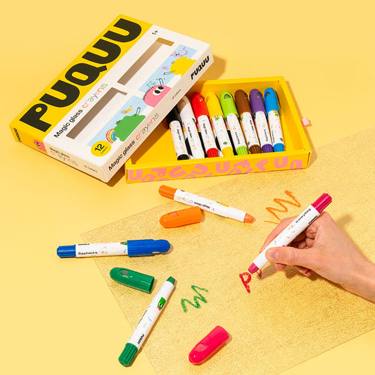 A set of colorful PUQUU magic markers shown with their box, loose markers, and a hand writing