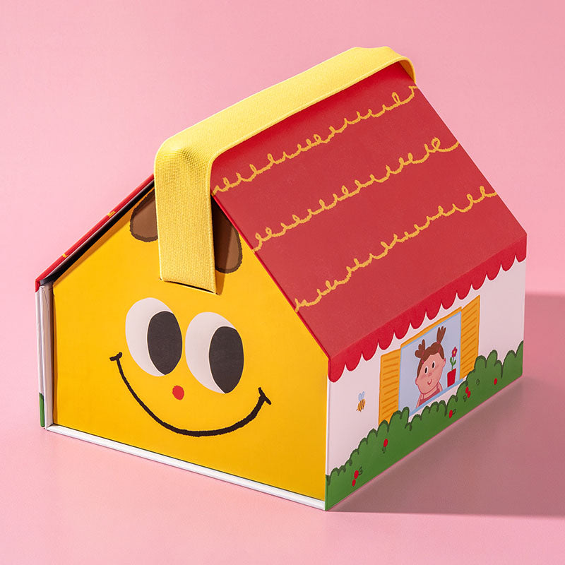 A colorful house-shaped gift box or container with a yellow body, red roof, yellow handle, and playful cartoon face details