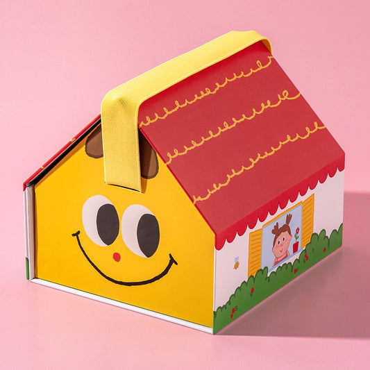 A colorful house-shaped gift box or container with a yellow body, red roof, yellow handle, and playful cartoon face details