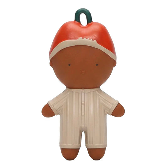A stylized plastic toy figure with a brown face and limbs, wearing a red and white hat and a cream-colored striped romper, featuring a dark green hanging loop on top.
