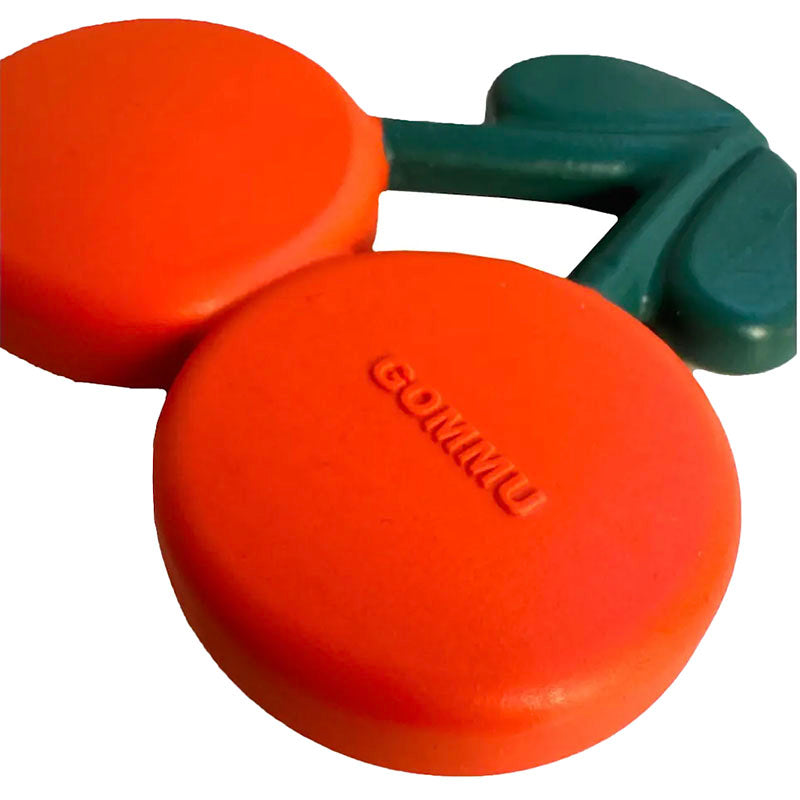 A red and green plastic baby teether toy shaped like a cherry, with the brand name 'GOMMU' embossed on the front orange piece.