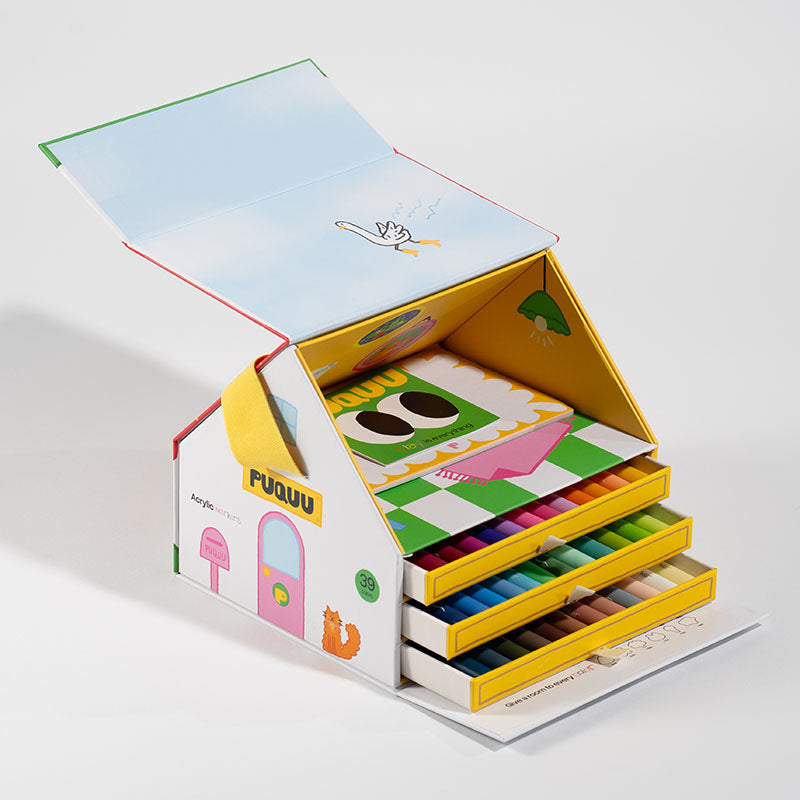 A children's acrylic paint set in a house-shaped box with open drawers and a hinged lid, photographed on a clean white studio background. The set includes multiple colored paint tubes and matching paint cards, with the brand name PUQUU visible on the front.