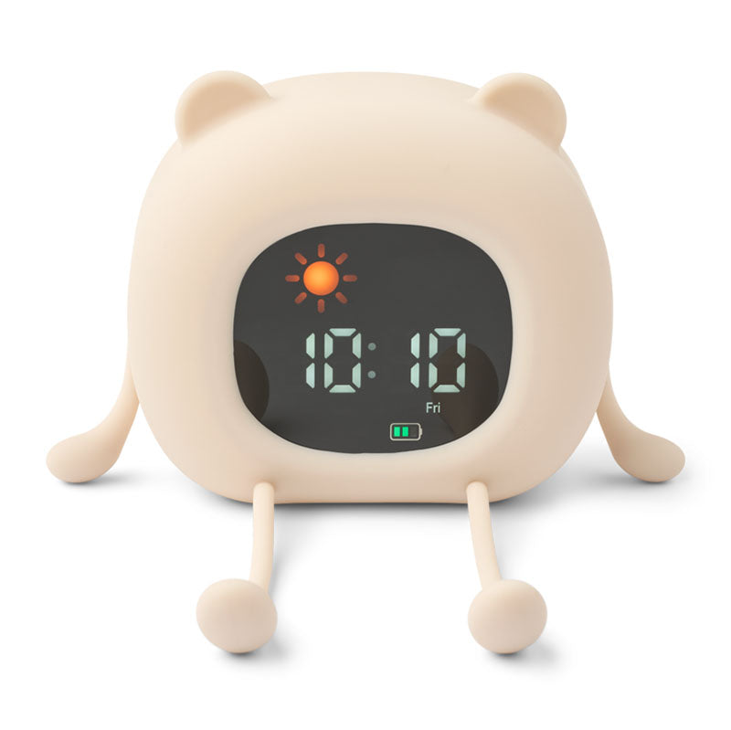 A cute, bear-shaped digital alarm clock in a warm cream color, featuring small ears, legs, and feet, with a black display screen showing the time and weather icon.