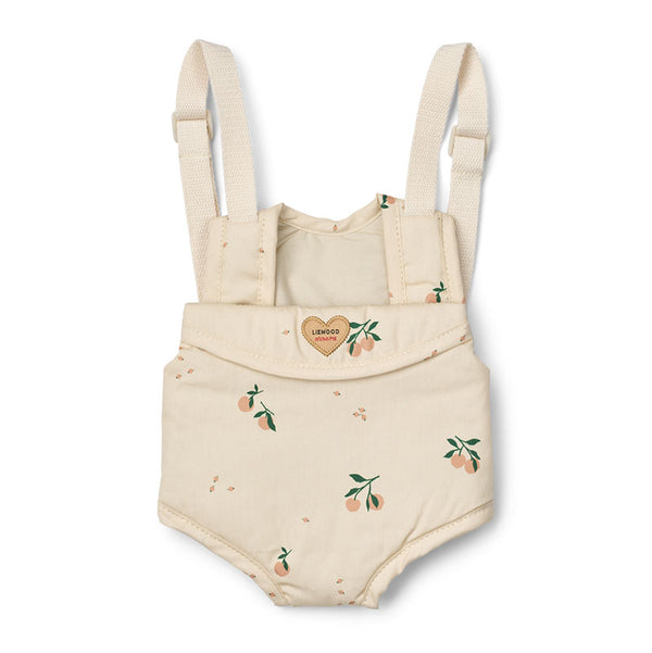 A Liewood doll carrier with adjustable shoulder straps, featuring a small peach and green leaf print scattered across the fabric and a small heart-shaped patch on the front flap.