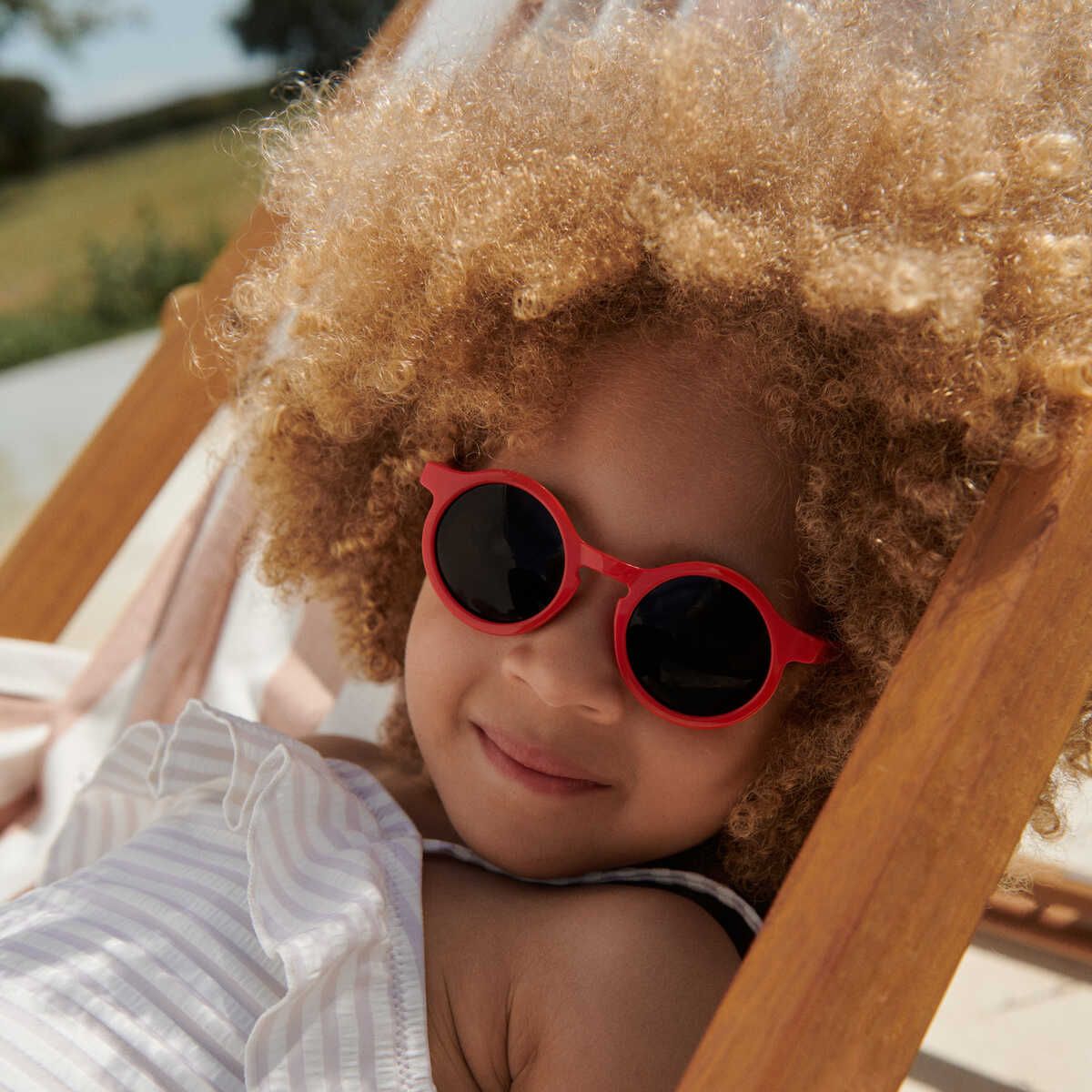 Mode für kleine mädchen und herzförmige sonnenbrille auf isoliertem rotem  hintergrund im kindertrend-urlaubsstil oder im kühlen sommer. lächeln sie  glücklich und kind mit brille für augengesundheit, wellness oder  sonnenschutz